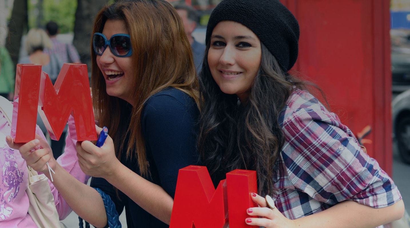 <p>Two smiling women holding Metro Bank M's.</p>