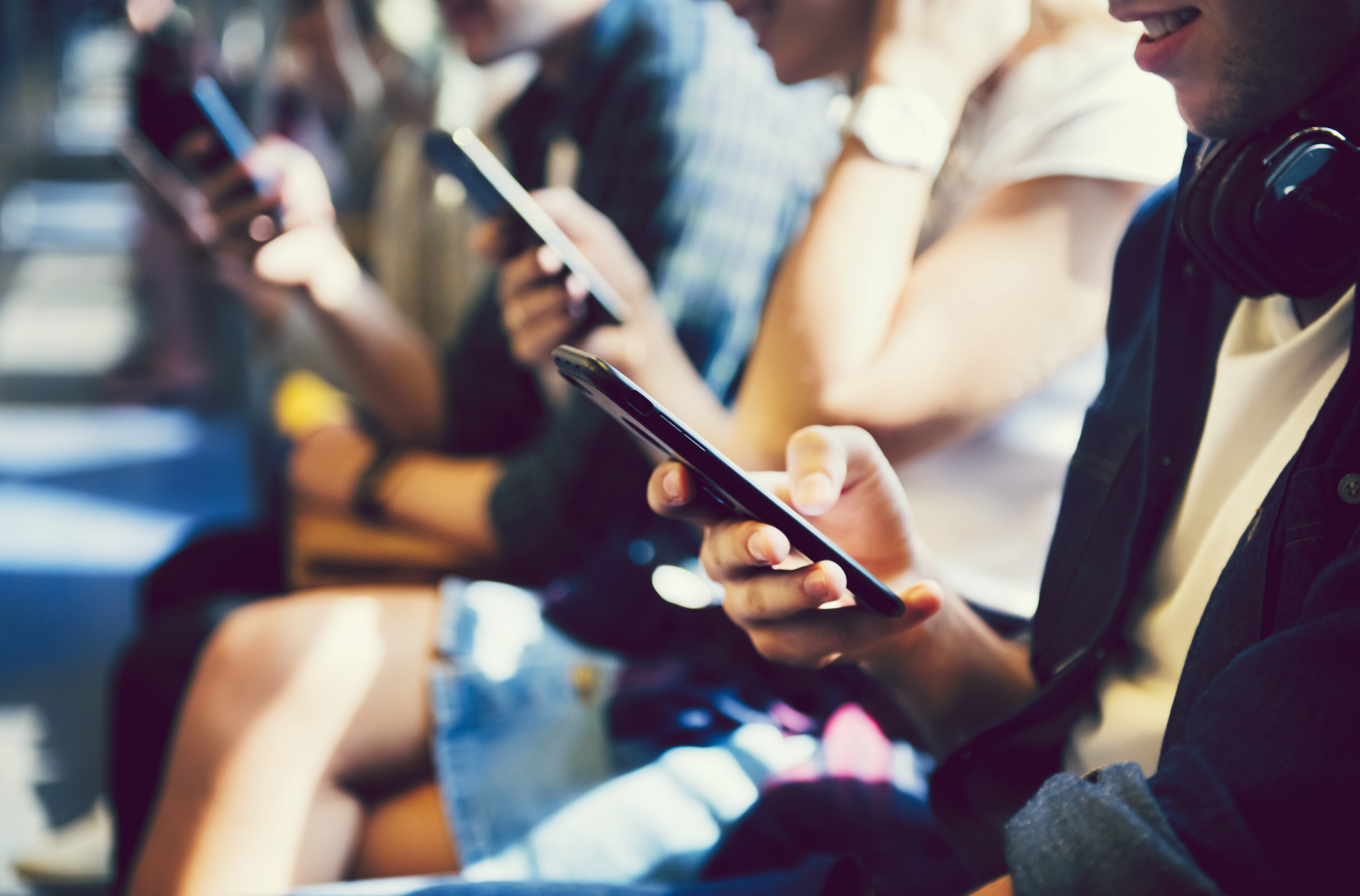 <p>A group of diverse people sitting next to each other using their phones.</p>