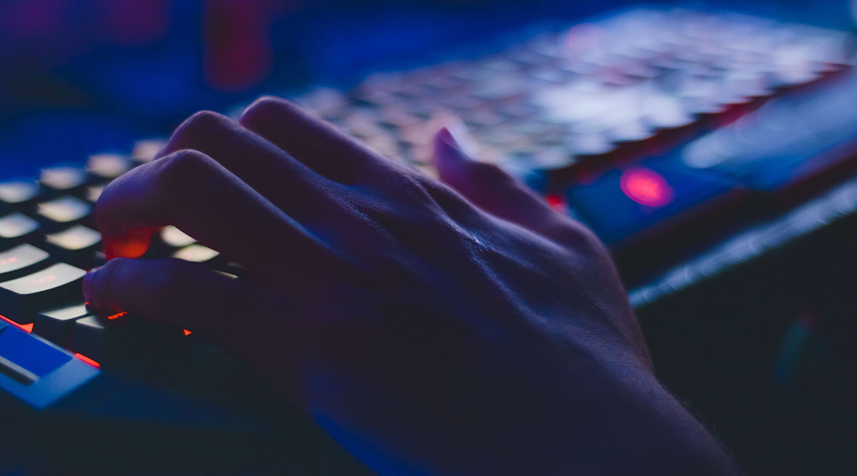 <p>A dark close up of a keyboard with a hand.</p>