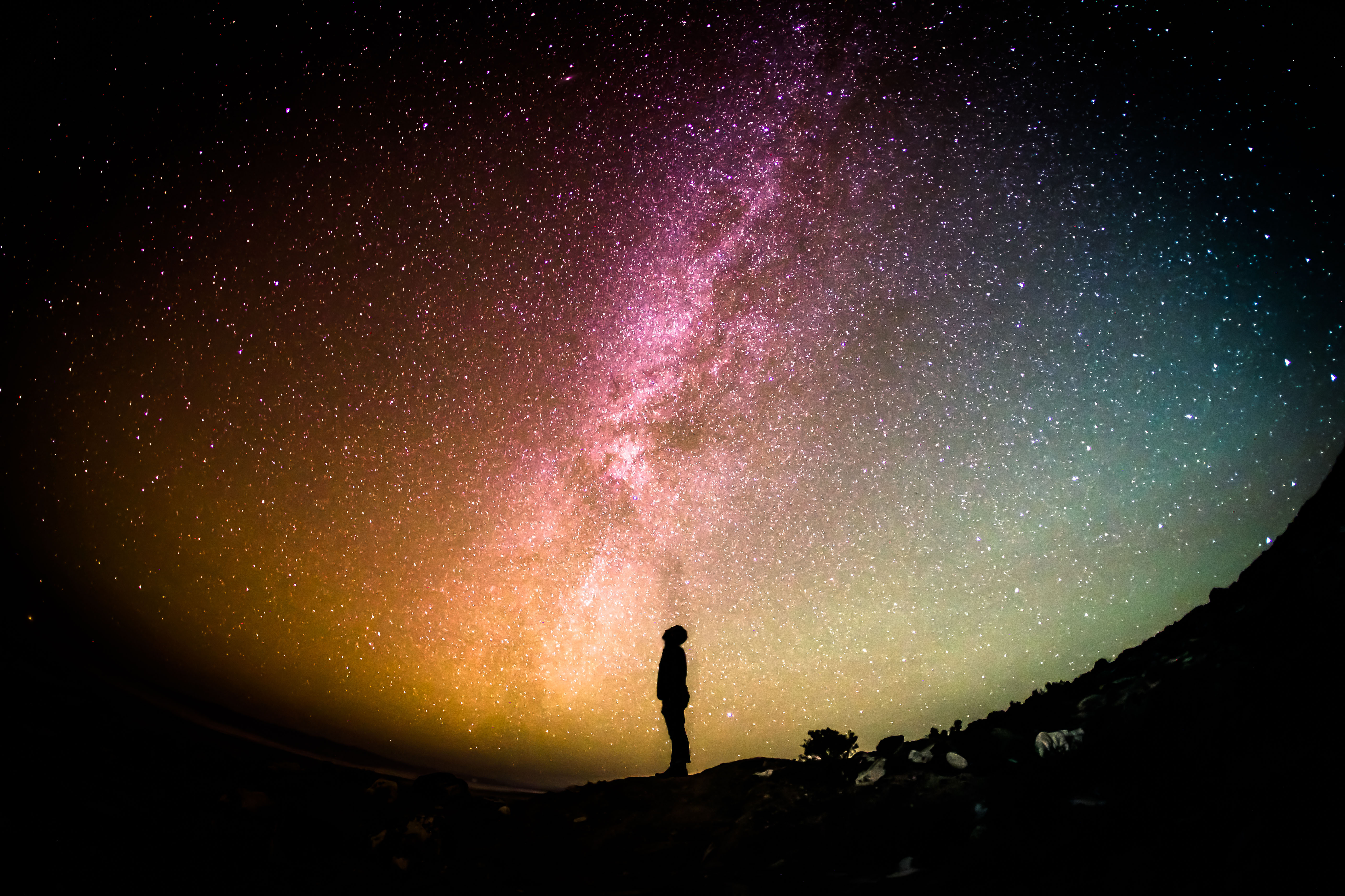 <p>A small silhouette of a person standing looking up on to the night sky.</p>