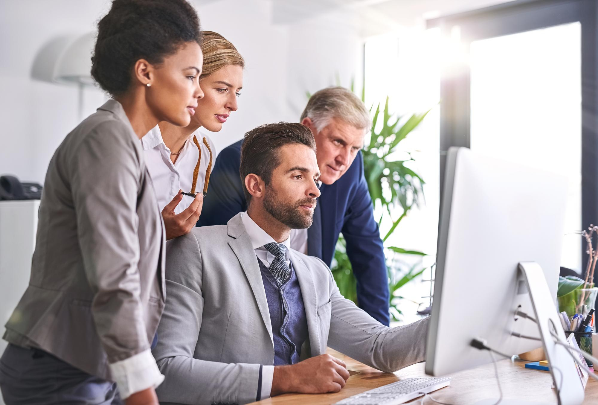 <p>Business team looking at a computer screen in an office.</p>