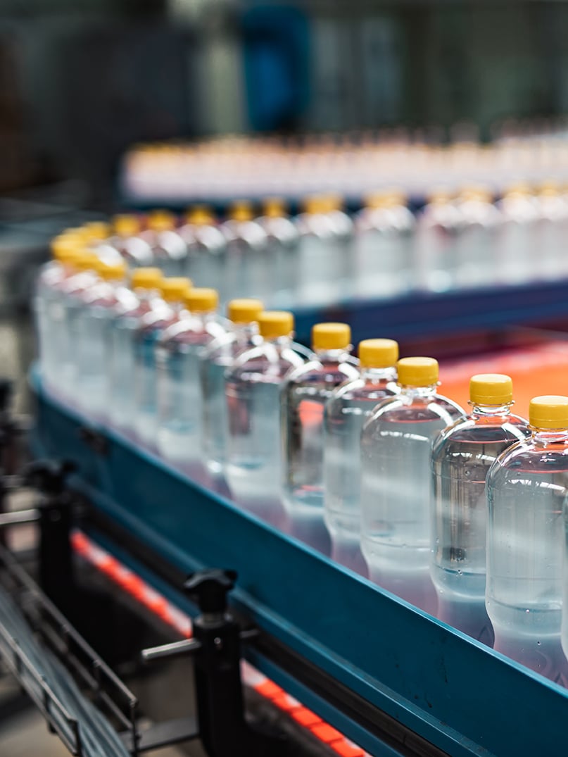 Une ligne de bouteilles d'eau en plastique transparent avec des bouchons jaunes sur un tapis roulant dans une usine de fabrication.