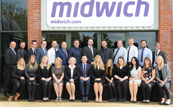 Group of professionally dressed people posing for a photo in front of a building with a