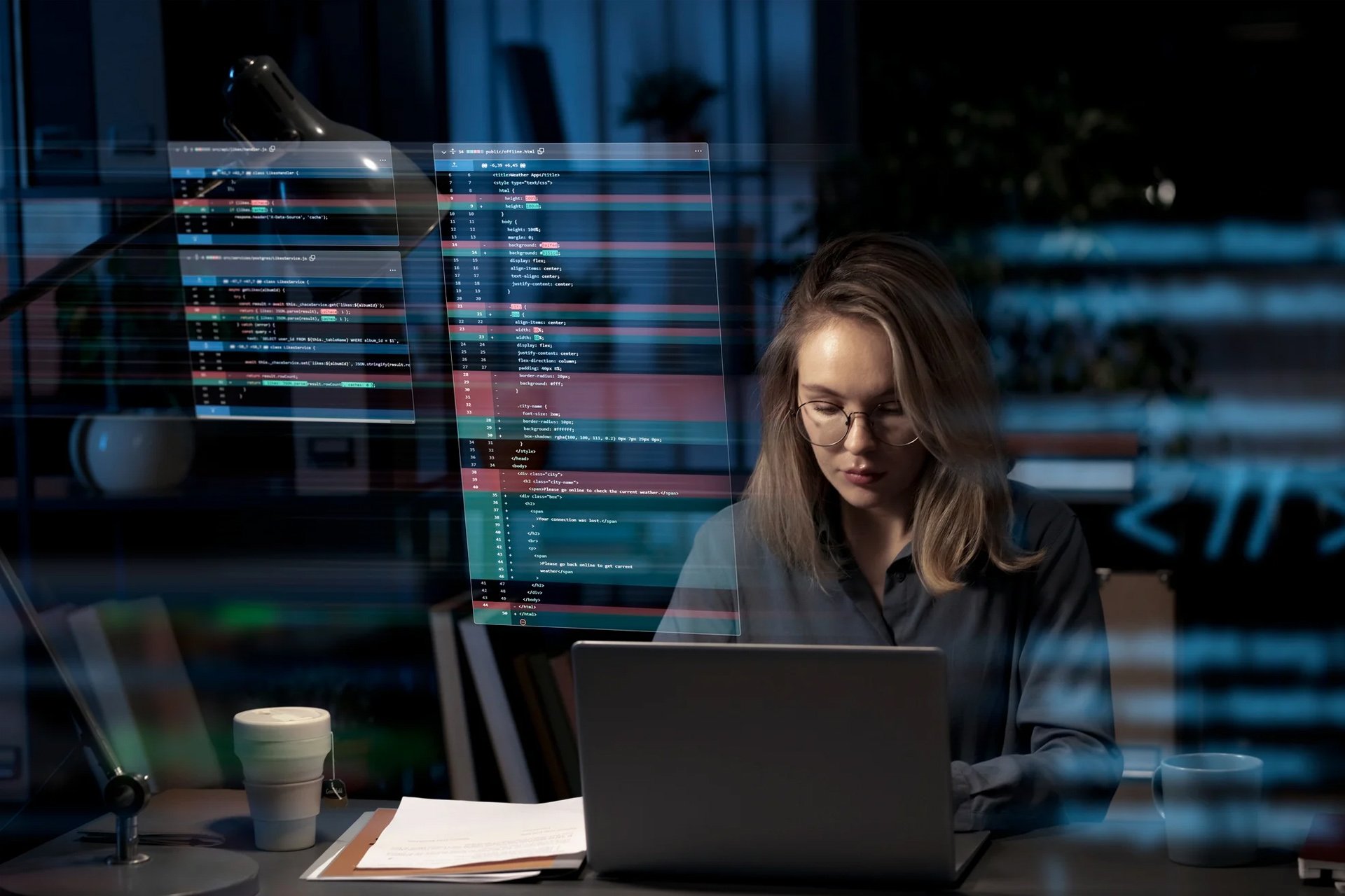 Woman with glasses working on a laptop in a dark office, with holographic code projections.