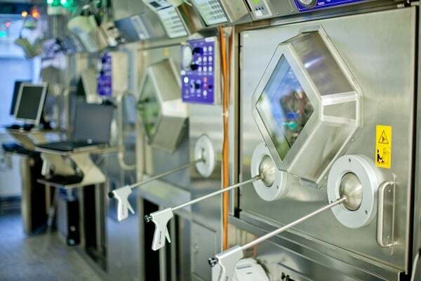 Sterile laboratory isolators with glove ports and control panels for handling sensitive materials.