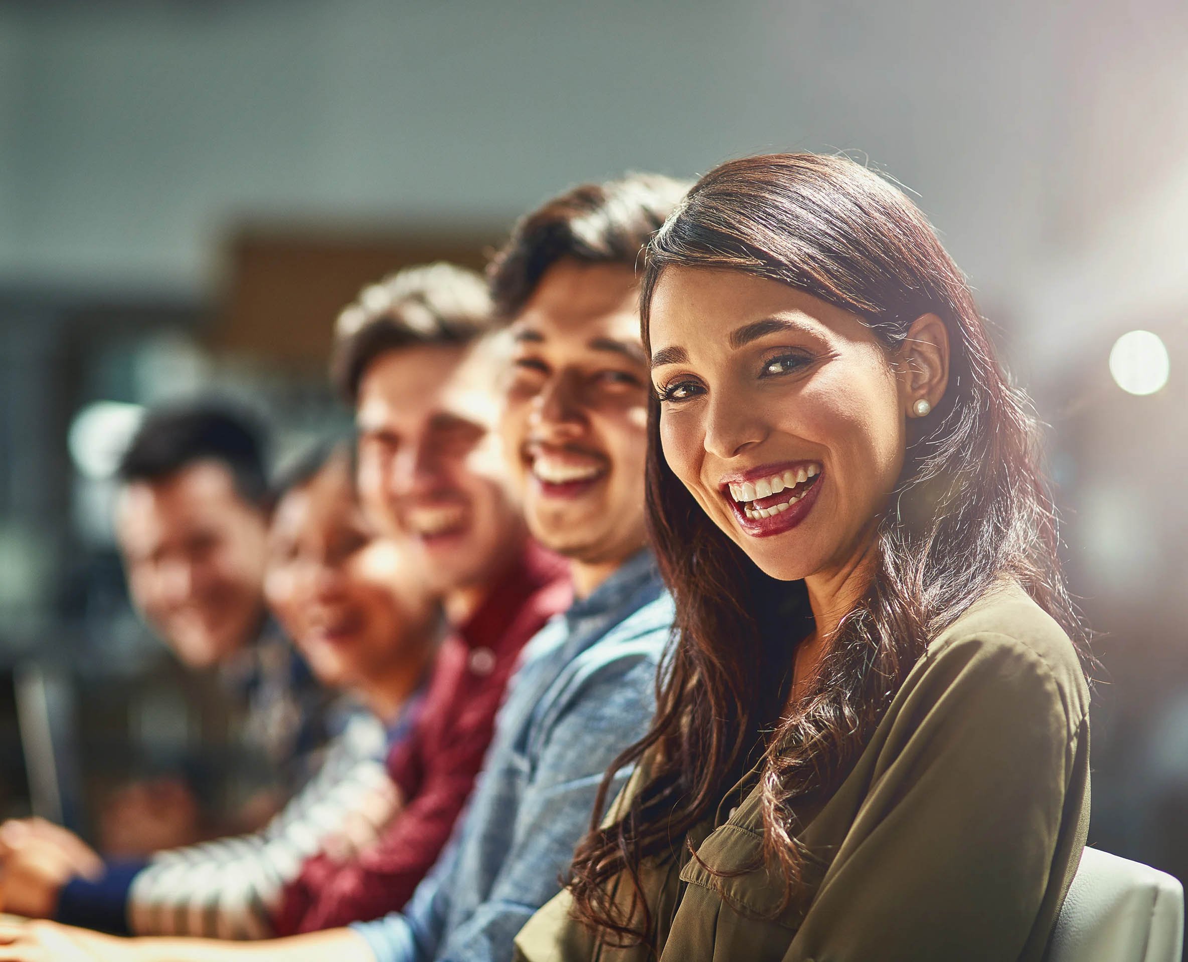 A diverse group of individuals seated in a conference setting, focused and engaged, with soft lighting illuminating the scene.