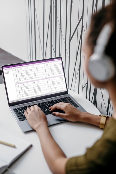 A person wearing headphones is typing on a laptop displaying the Platina interface from Formpipe, set against a minimalist black-and-white wall design.