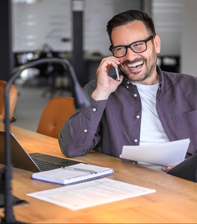 cheerful-male-manager-glasses-discussing-project-details-smart-phone-desk-modern-office-1